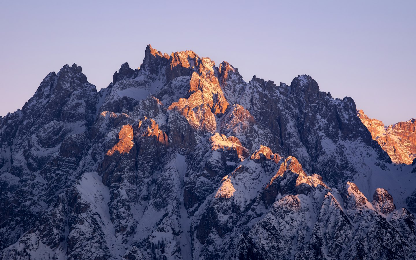 Montagne innevate illuminate dalla luce dorata dell'alba.