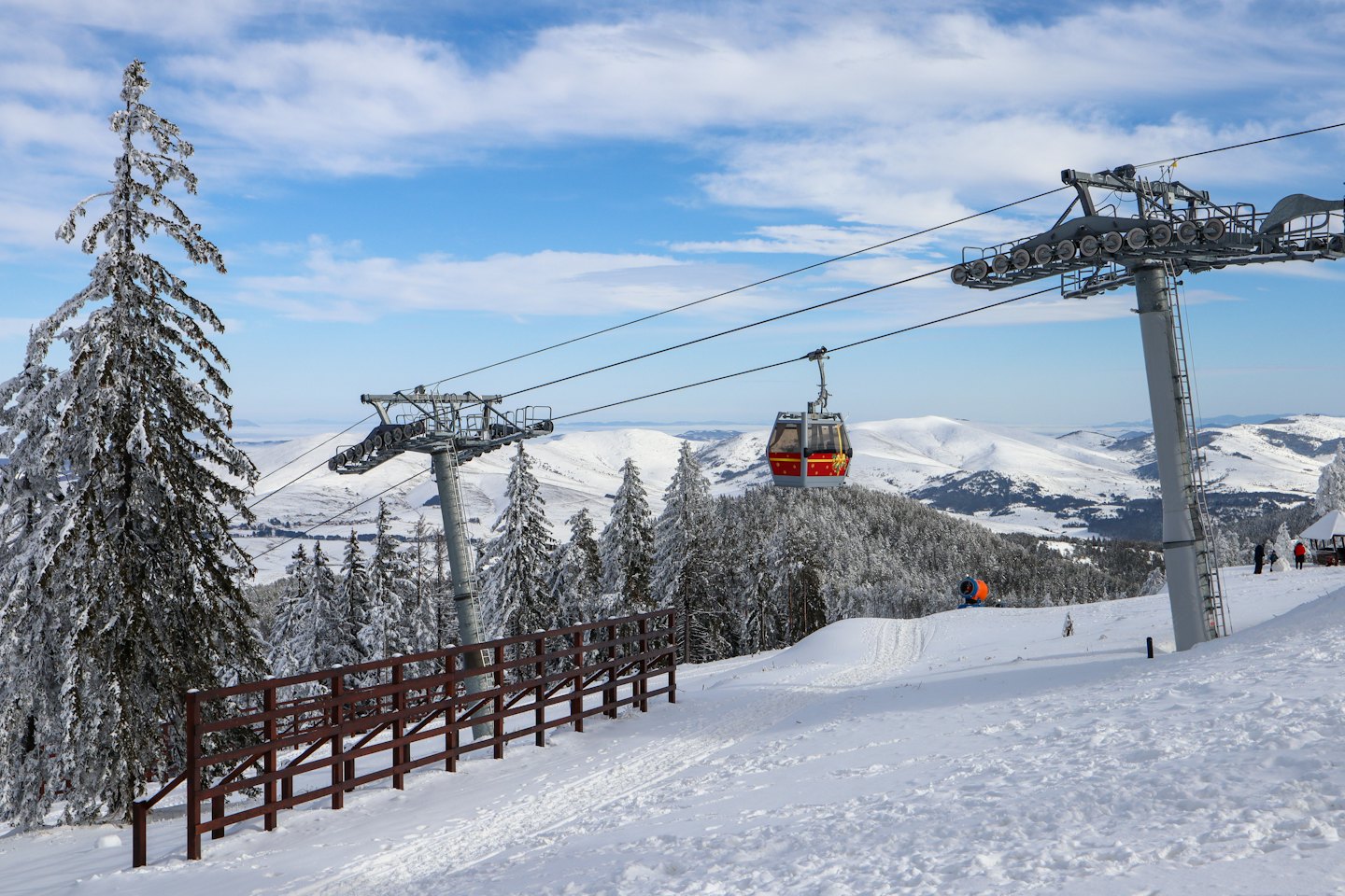 Una gondola rossa e gialla viaggia su montagne innevate.