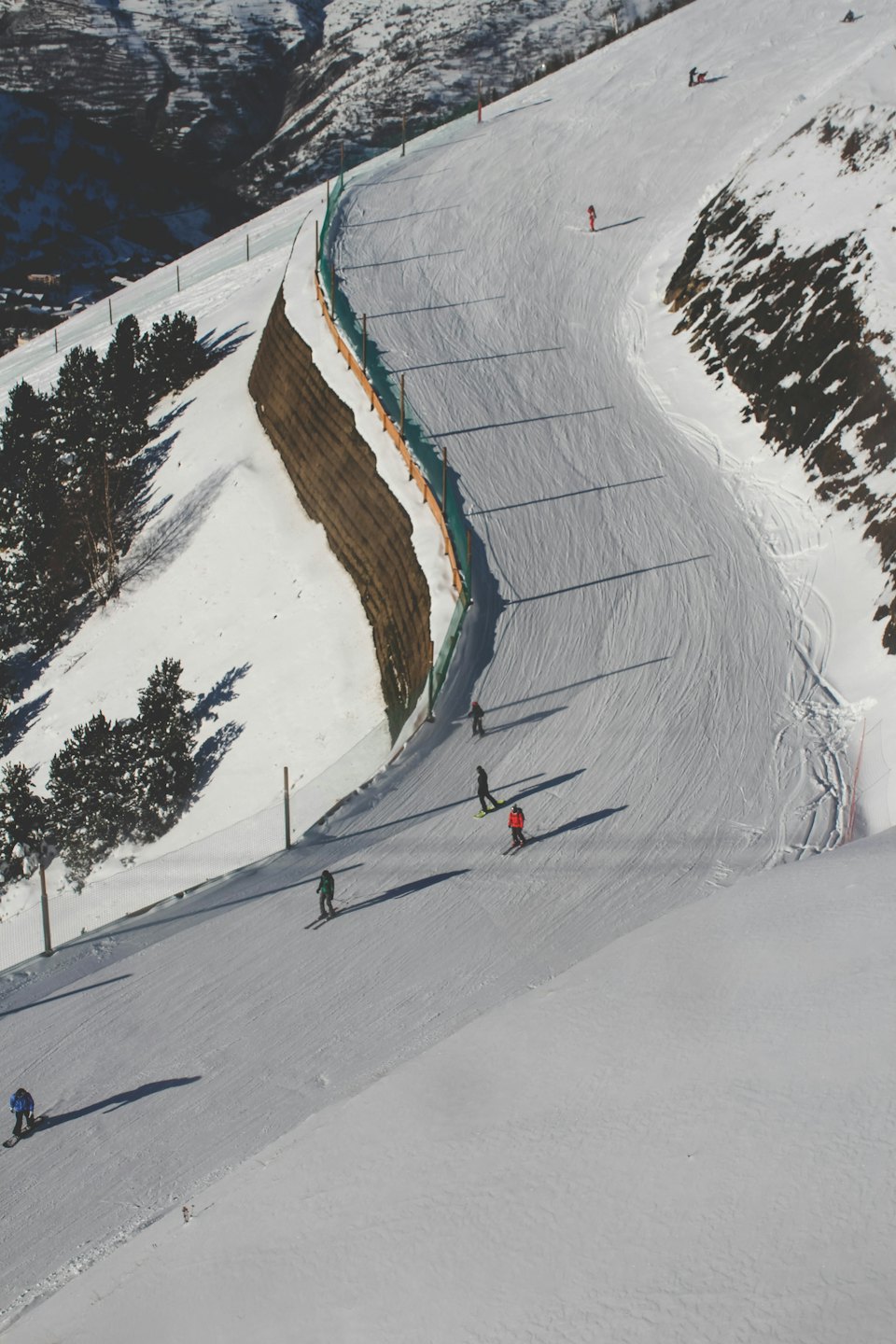 Sciatori e snowboarder su un pendio montano soleggiato.