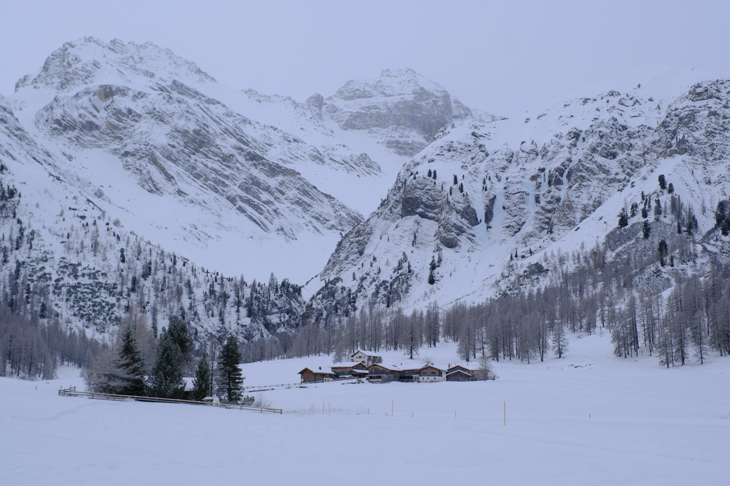 Chalet di legno in una valle innevata sotto alte montagne.